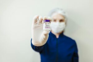 Healthcare worker holding a Botox vial in a clinical setting, wearing protective gear.