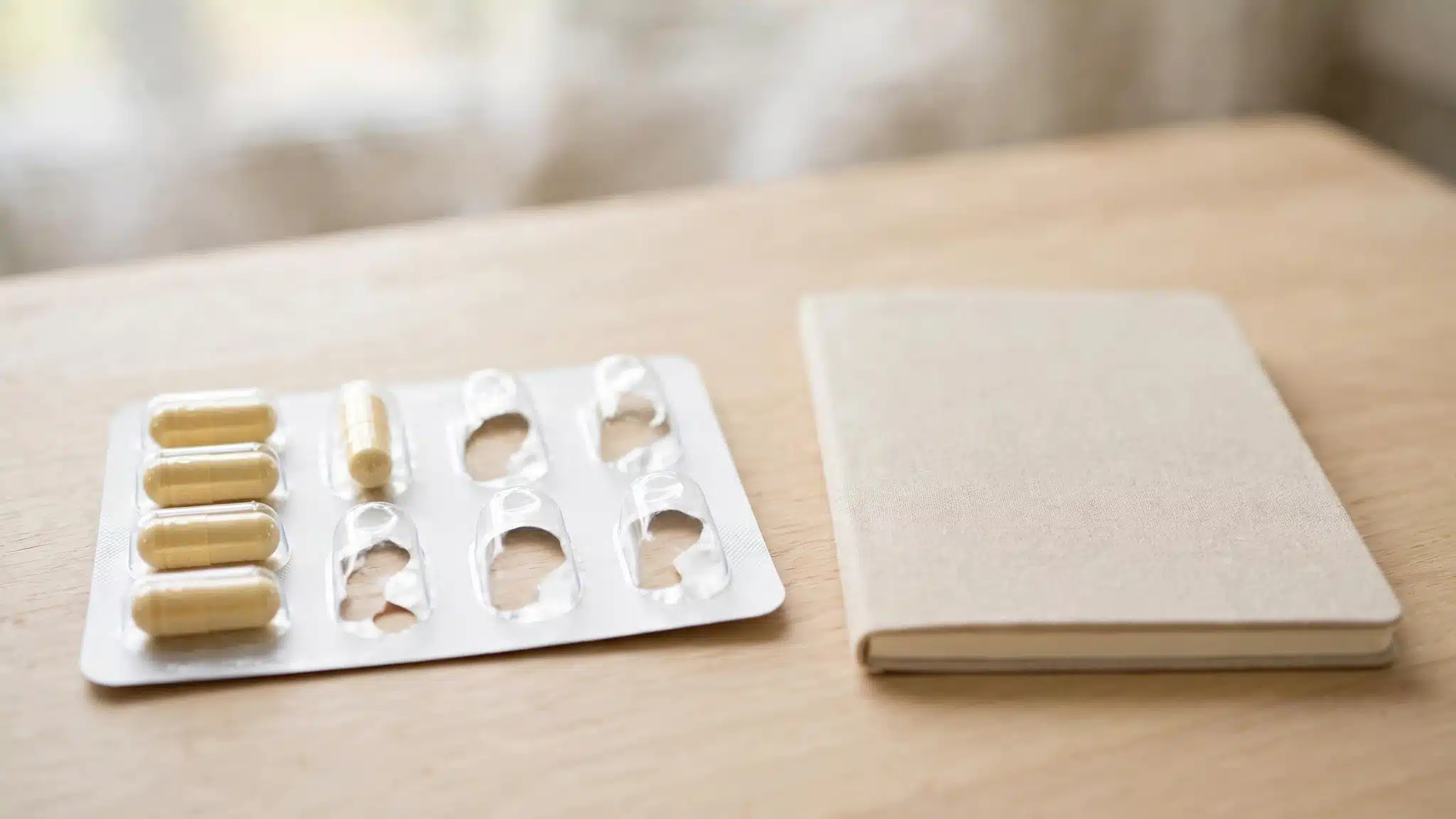 Blister pack beside a notebook and pen