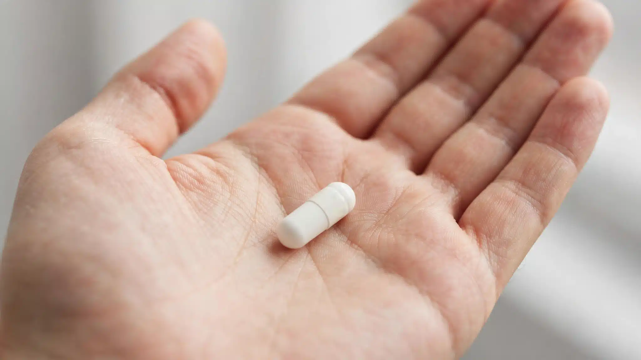 Single plain capsule resting in an open palm