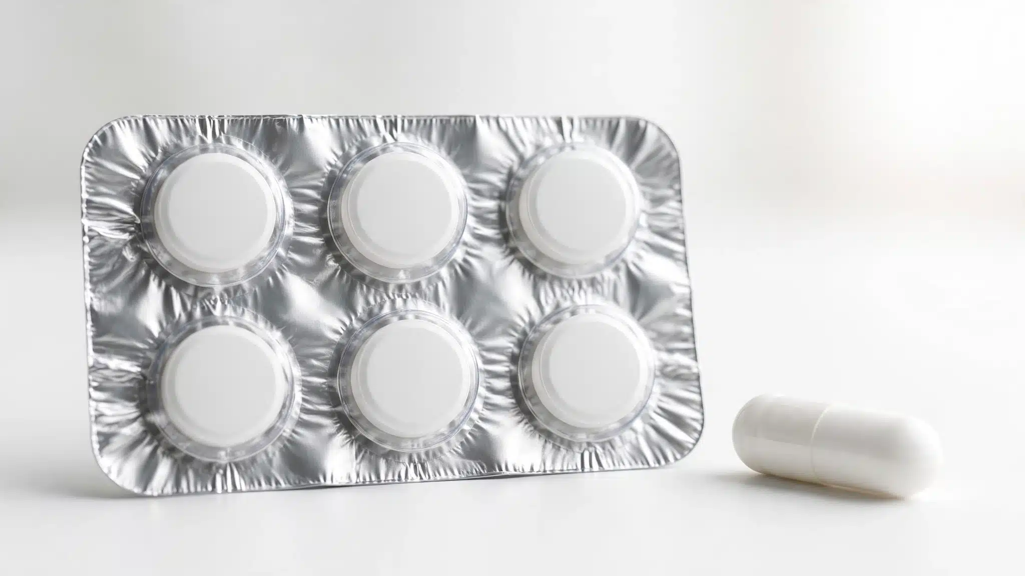 Blister sheet of tablets beside a single capsule